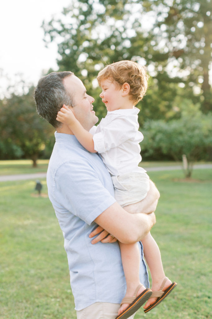 A Dad Holding His Toddler Son And Smiling