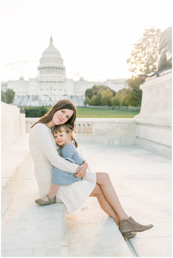 Mama And Daughter Sitting Together, Hugging, In Front Of The Us Capitol Building In Dc