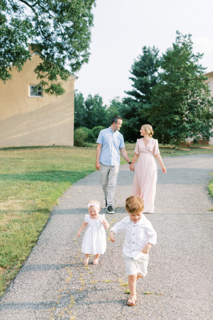 Two Young Children Running Ahead Of Their Parents During A Maryland Family Photo Session