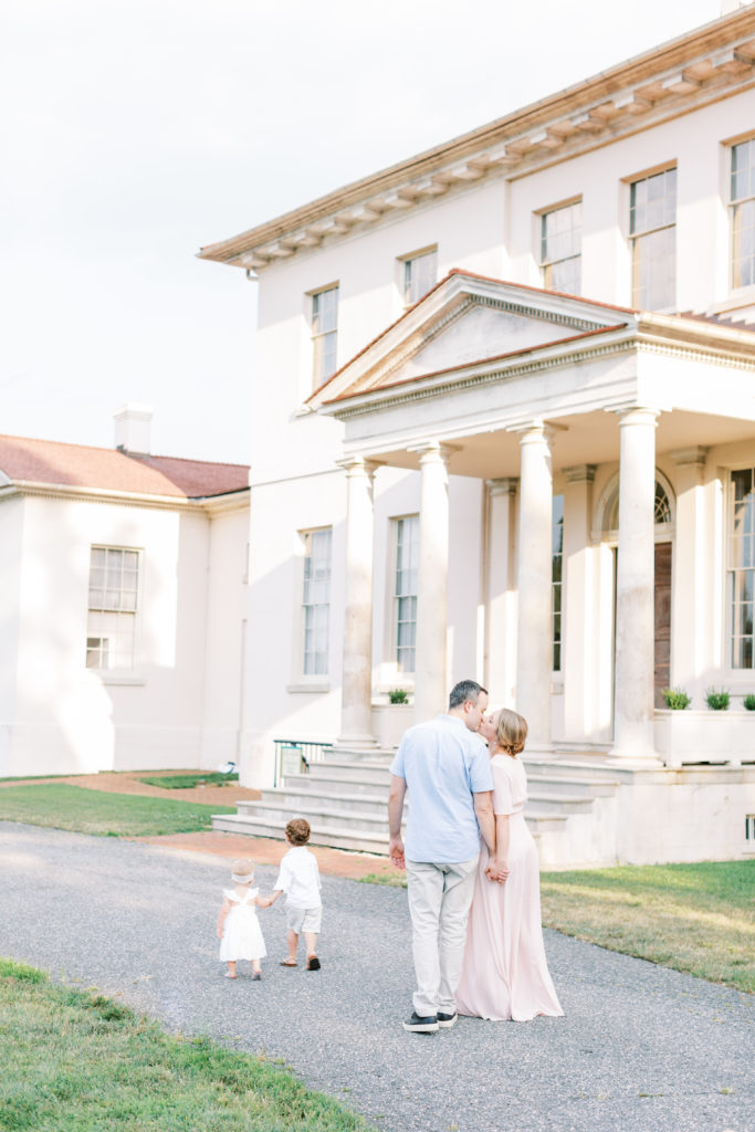 Parents Kissing While Their Two Children Walk Ahead During A Maryland Family Photo Session