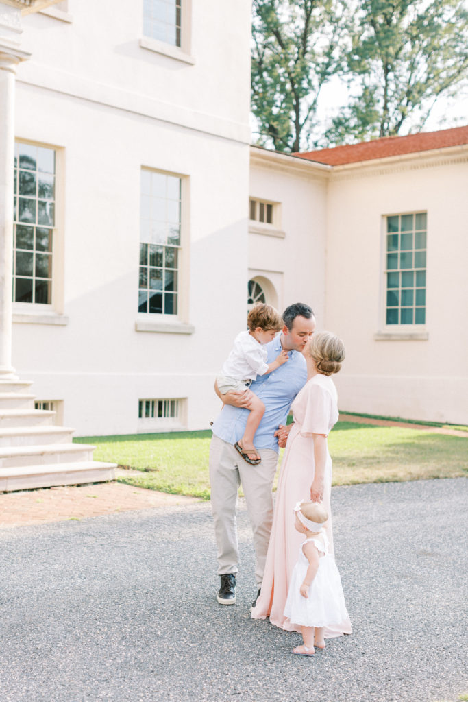 Mother And Father Kiss During A Family Photo Session.