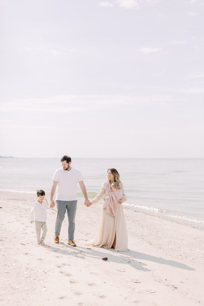 A Family Traveling With A Baby Walking On A Beach