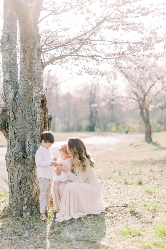 A Mother Kneels Down To Look At The Flowers Her Son And Daughter Picked For Her.