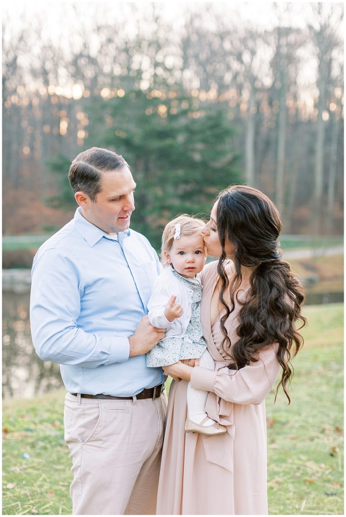 Mother Kisses Toddler Daughter During Family Photography Session.