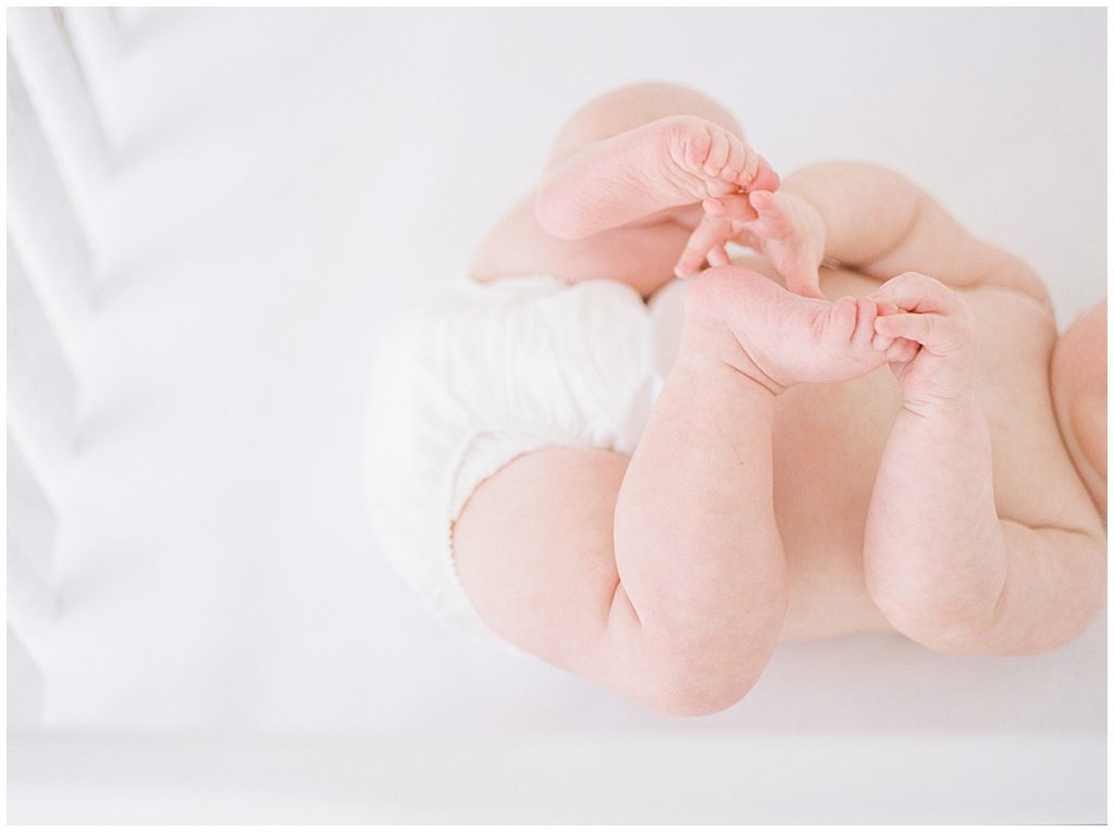 Baby Grabbing Her Baby Toes Laying In A Crib.