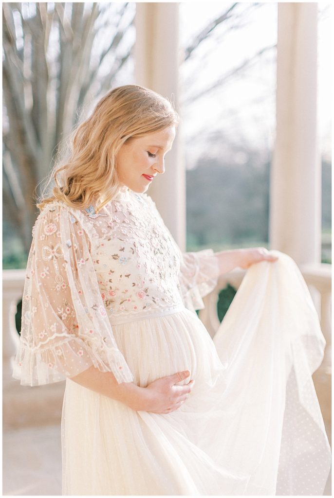 Pregnant Woman Holds Up Dress During Maternity Session At The Great Marsh Estate In Northern Virginia