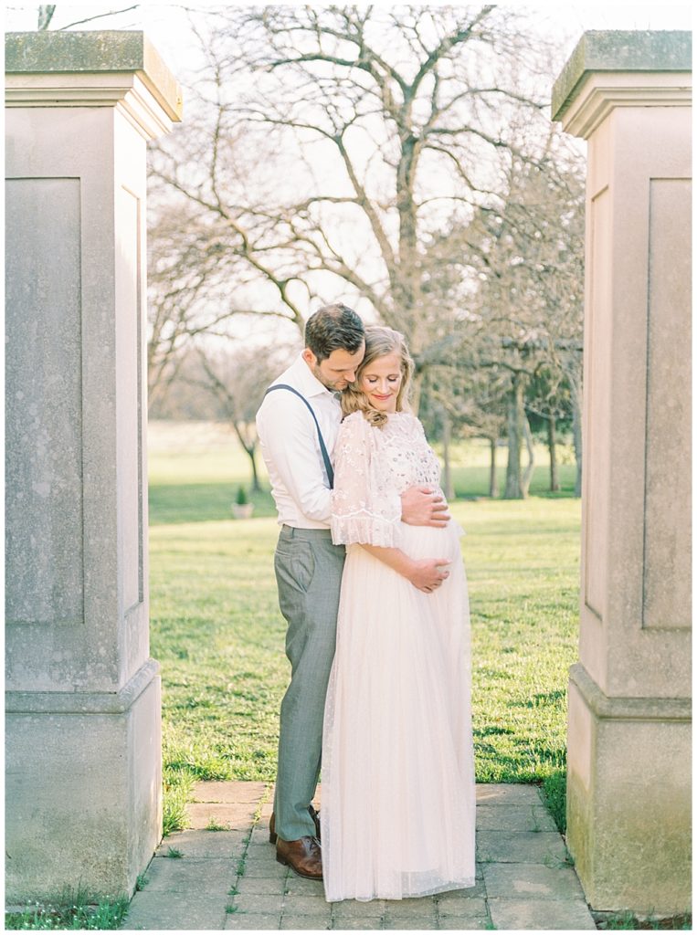 Father Cradles His Wife During Their Maternity Session At The Great Marsh Estate In Northern Va.