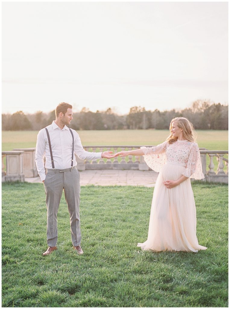 Husband And Wife Hold Hands During Maternity Photo Session At The Great Marsh Estate