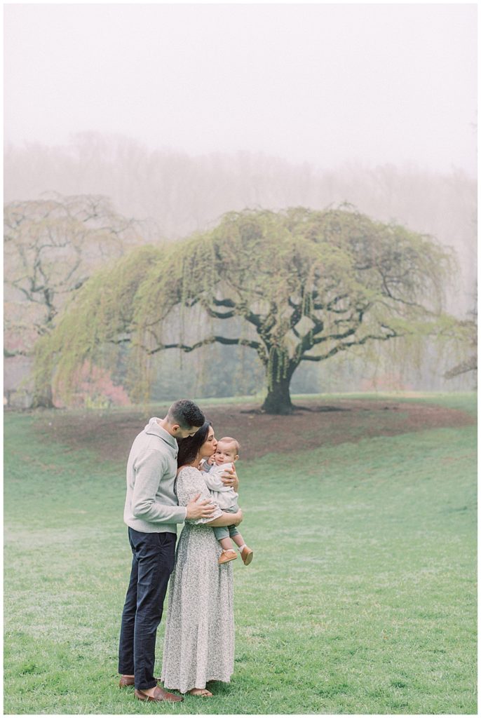 Mother, Father, And Baby Stand In Field In Brookside Gardens In Silver Spring, Maryland.