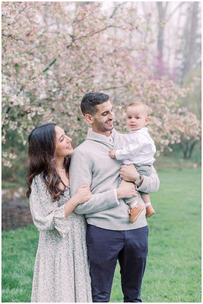 Young Family Stands By A Cherry Blossom Tree At Brookside Gardens In Silver Spring.