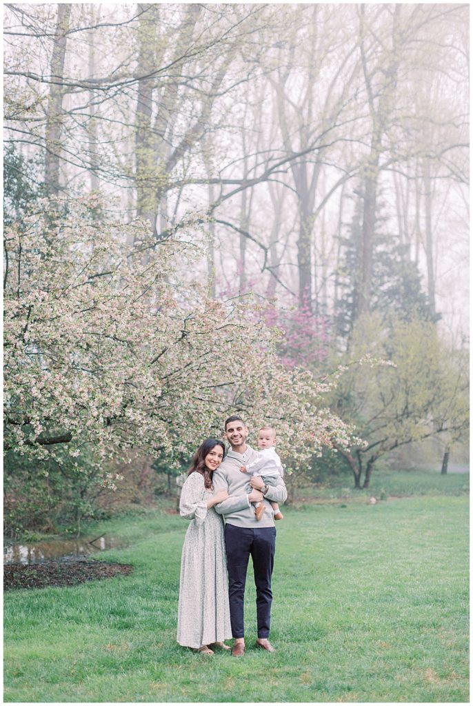 Young Family Stands Next To A Cherry Blossom Tree During A Brookside Gardens Photo Session In Silver Spring.