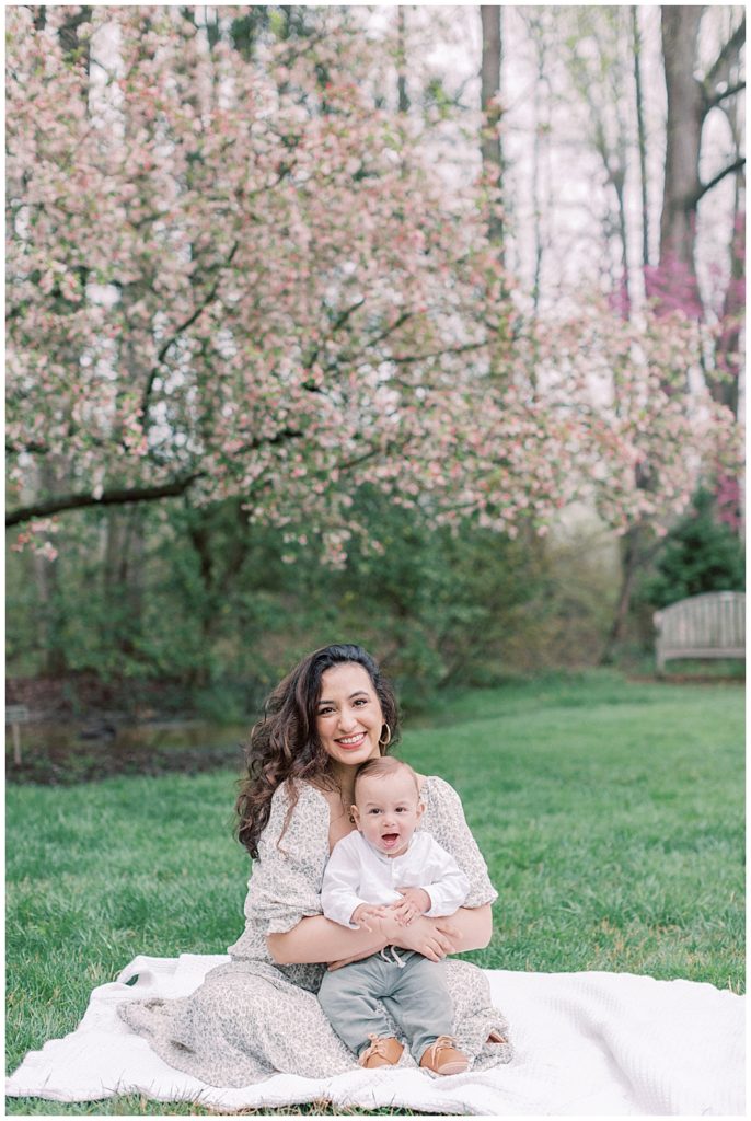 Mother Holding Her Son On Her Lap During Family Photo Session In Maryland Garden.