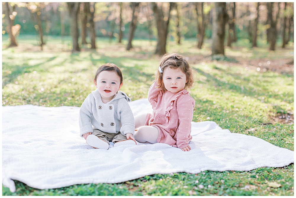 Two Young Children Sit On A Blanket By The National Arboretum Cherry Blossoms