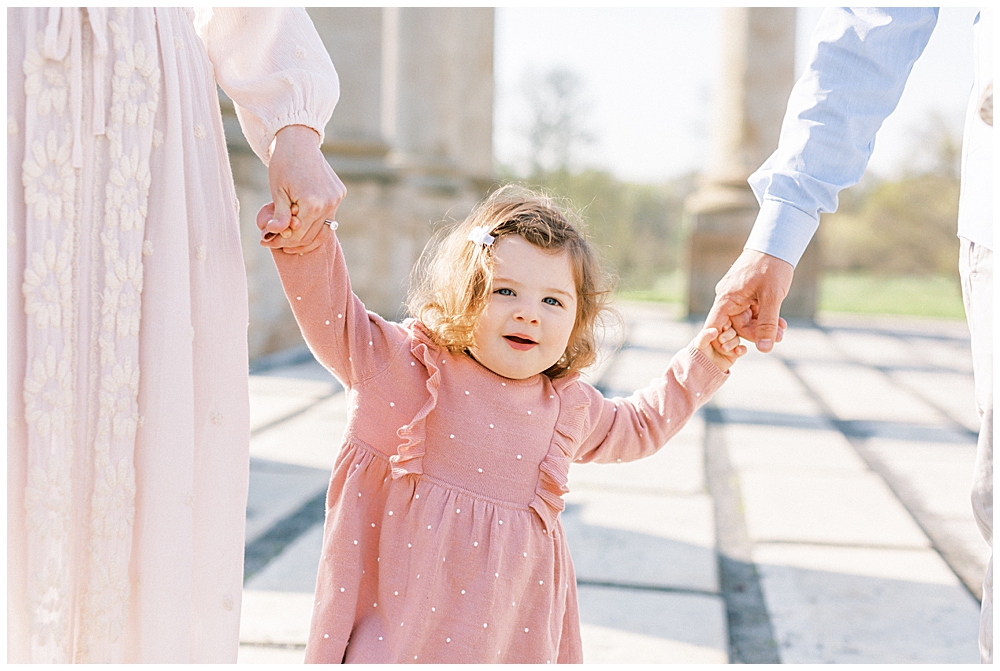 Little Girl Holding Her Mother And Father's Hands Walking At The Capitol Columns At The National Arboretum