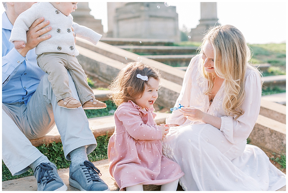 Family Sits On The Steps Of The Capitol Columns At The National Arboretum