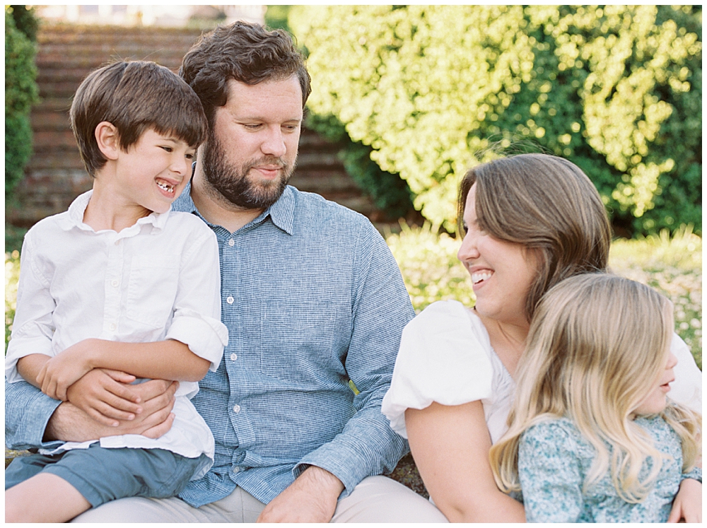 Family Smile At One Another While Sitting On Brick Steps