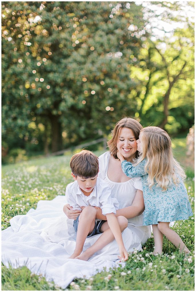 Daughter Kisses Her Mother While They Sit In A Field