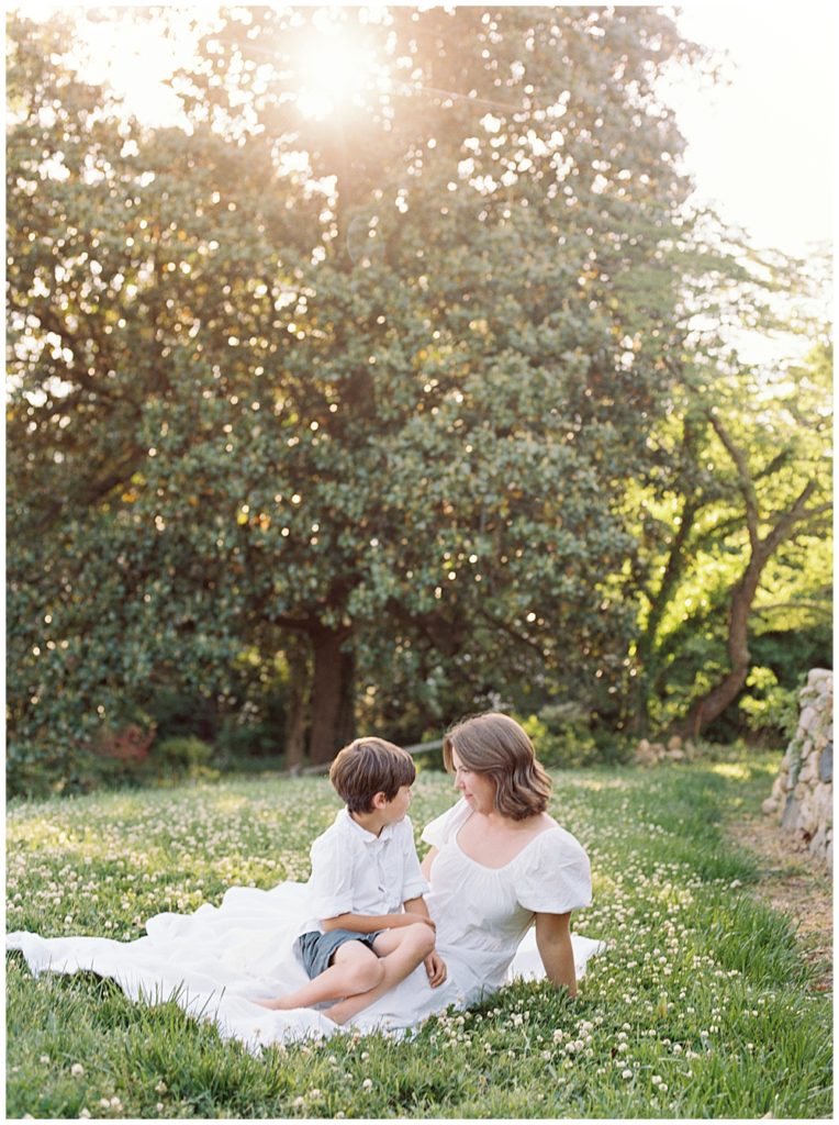 Mother Sits With Her Son During Sunset In A Field