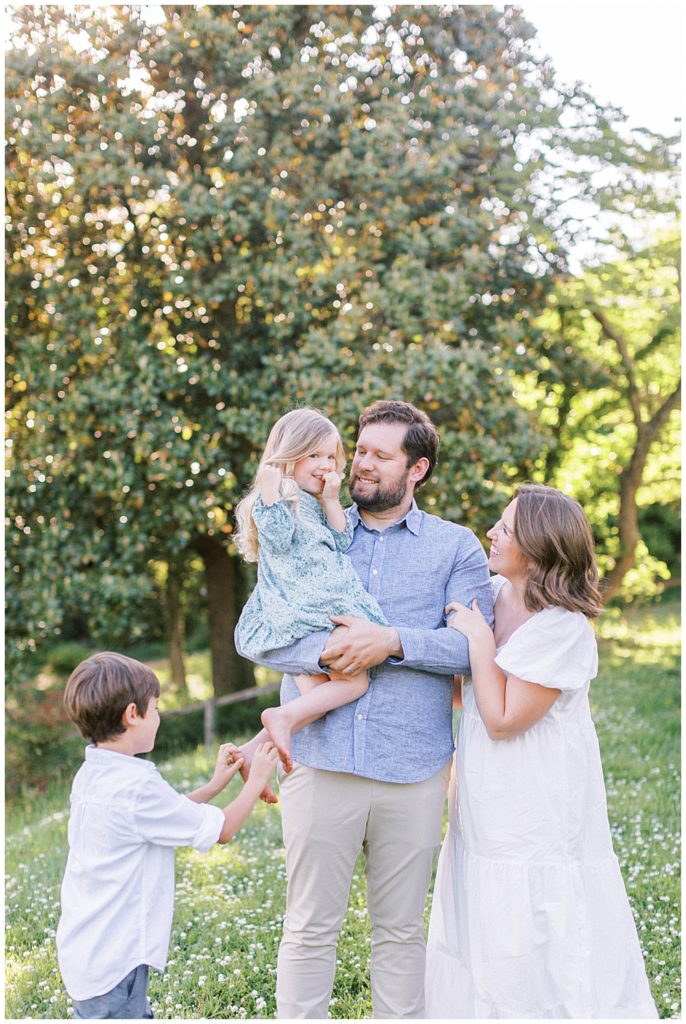 Family Smiles At One Another In A Field During Their Photo Session At Mulberry Fields