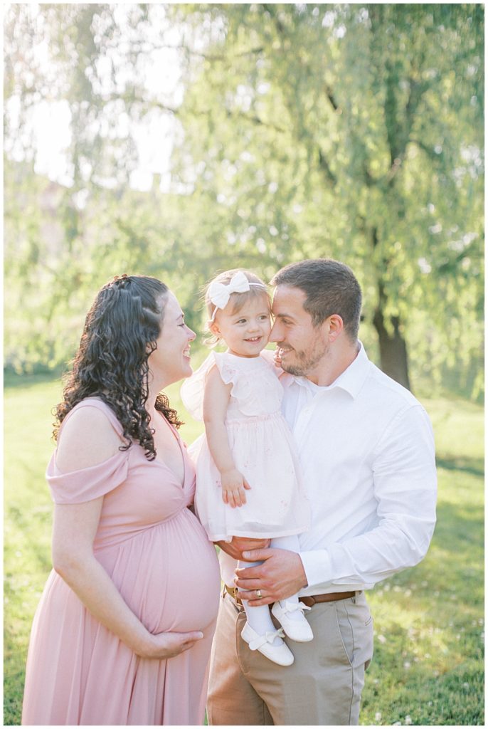 Mother And Father Snuggle Their Toddler Daughter During Their Maternity Session At Riversdale Manor