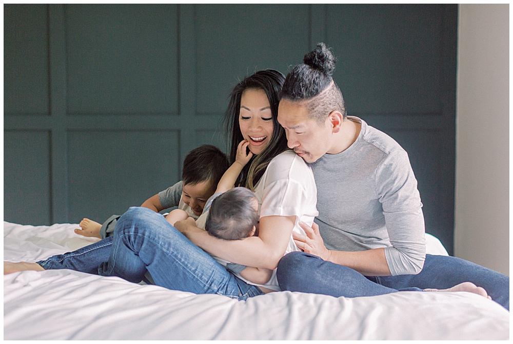 Father And Mother Look Down At Their Infant Who Is Nursing During Their Northern Virginia In-Home Family Session