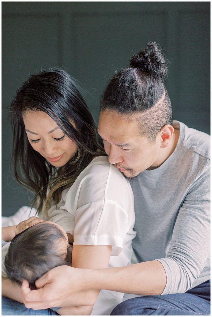 Nova Family Photographer | Father Kisses Mother's Shoulder While Their Infant Son Nurses