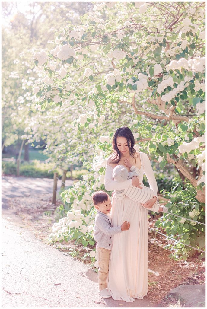 Mother Nurses Her Infant While Her Older Son Hugs Her At Brookside Gardens