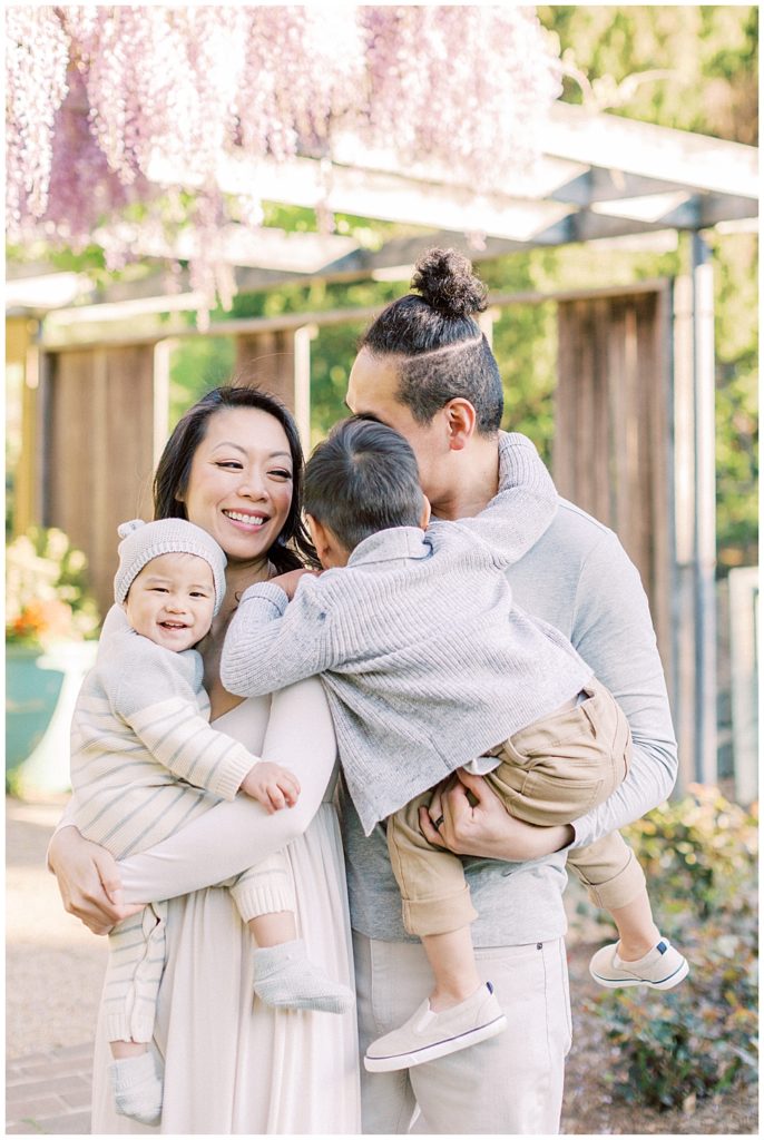 Family Stands Near Wisteria At Brookside Gardens And Little Brother Gives His Mother A Hug