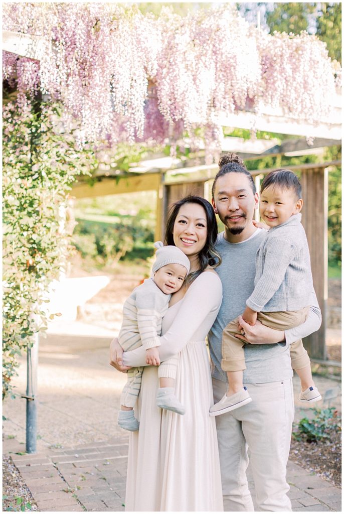 Family Stands Together For A Family Photo Session By The Wisteria At Brookside Gardens