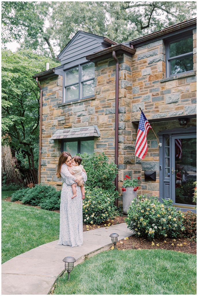 Mother Holds Her One Year Old Daughter In Front Of Her Home During Her Arlington Family Session