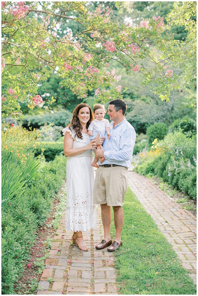 Parents Stand Holding Their Baby Boy At Tudor Place In Washington Dc