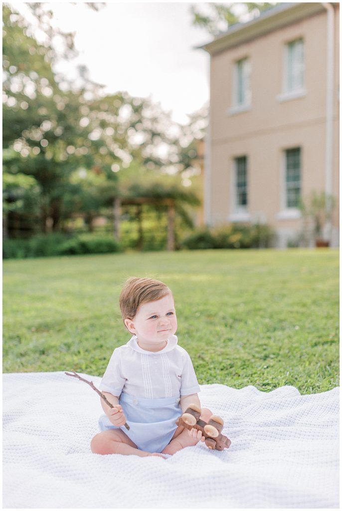 Baby Boy Sits On A Blanket In Front Of Tudor Place Manor