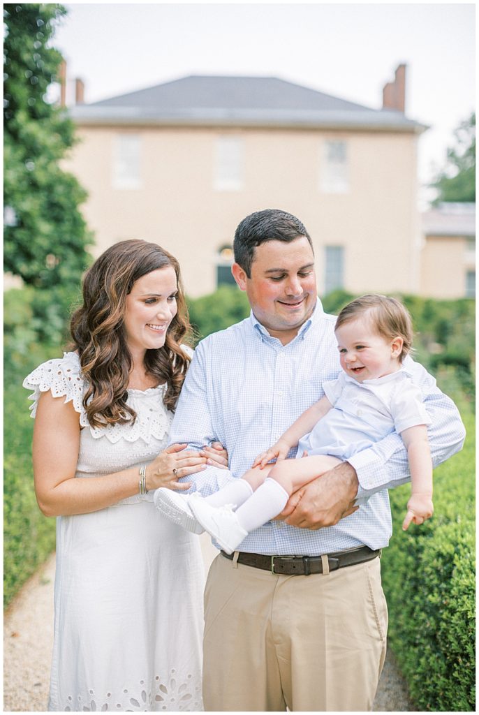 Baby Boy Laughs While His Mother And Father Hold Him During Their Family Session In Dc