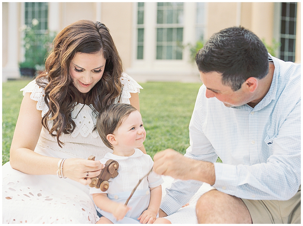 Mother And Father Play With Their Son On A Blanket Outside