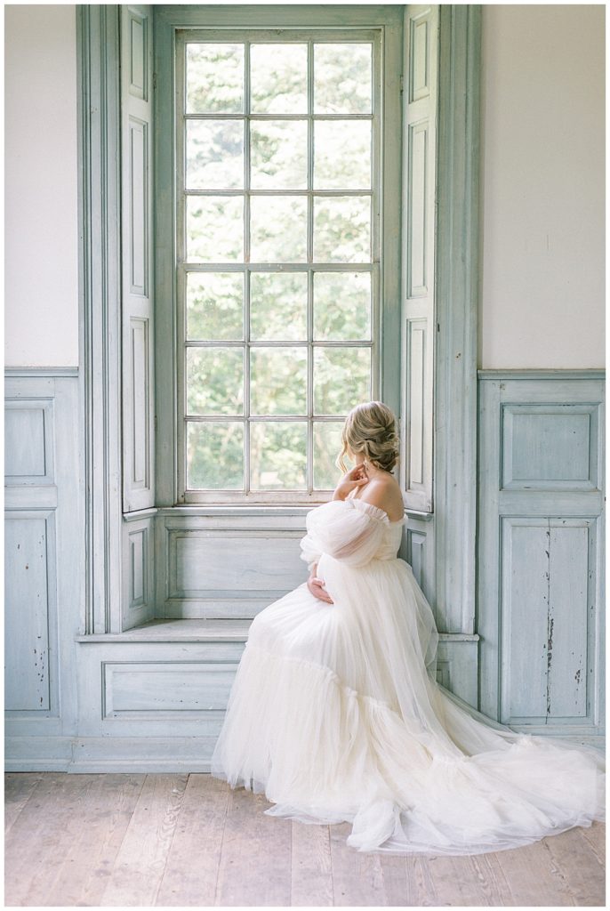 Woman Sits In Window During Her Salubria Maternity Photo Session In Northern Va