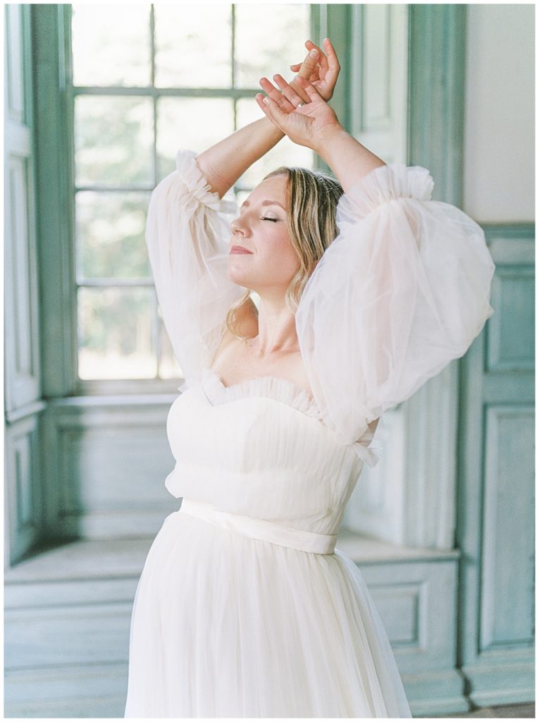 Washington Dc Maternity Photographer | Pregnant Woman Stands With Hands Over Her Head During Salubria Maternity Session