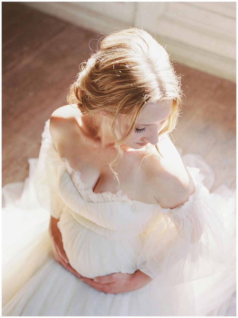 Light Hits A Pregnant Other As She Sits And Holds Her Belly