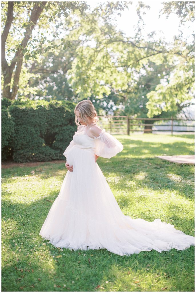 Elegant Maternity Session | Pregnant Mother Stands With One Hand Behind Her Back And One Hand Below Her Belly