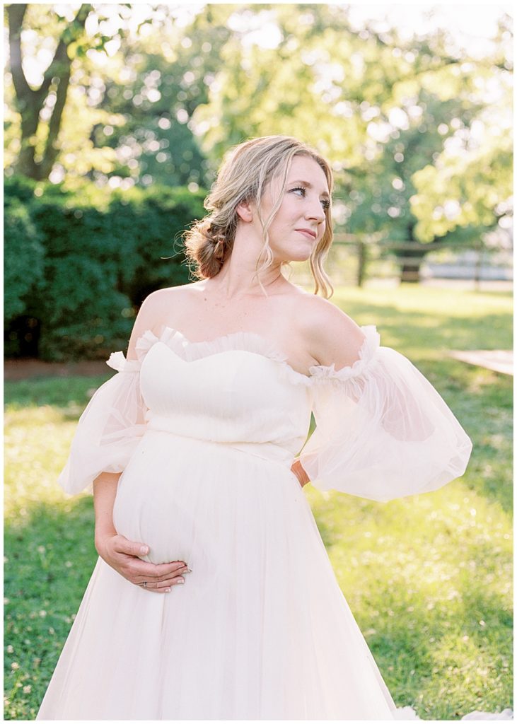 Dc Maternity Photographer | Pregnant Woman Holds Her Belly And Looks Over Her Shoulder During Her Northern Virginia Maternity Session