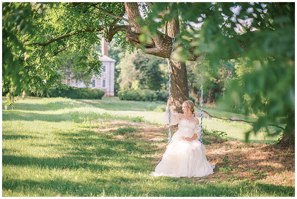 Pregnant Woman Sits On A Swing Looking Over Her Shoulder During A Salubria Maternity Photo Session In Northern Va