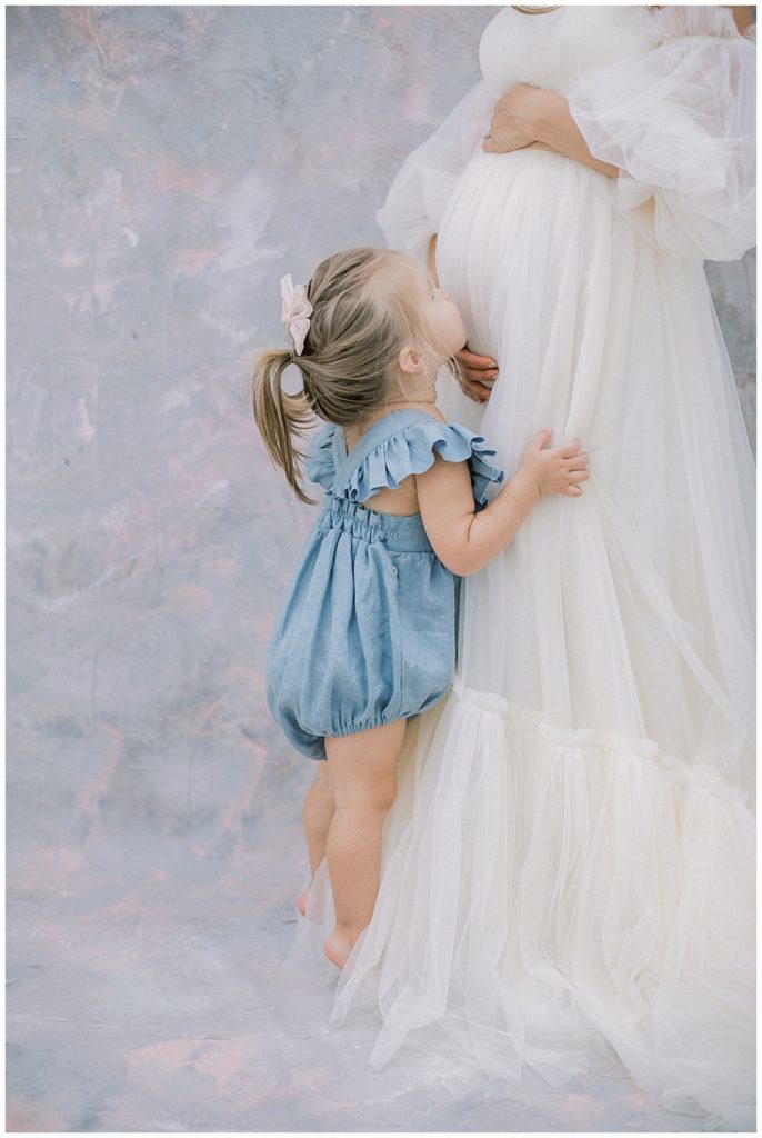 Little Girl Kisses Her Mother's Pregnant Belly During Their Motherhood Studio Session In Washington Dc