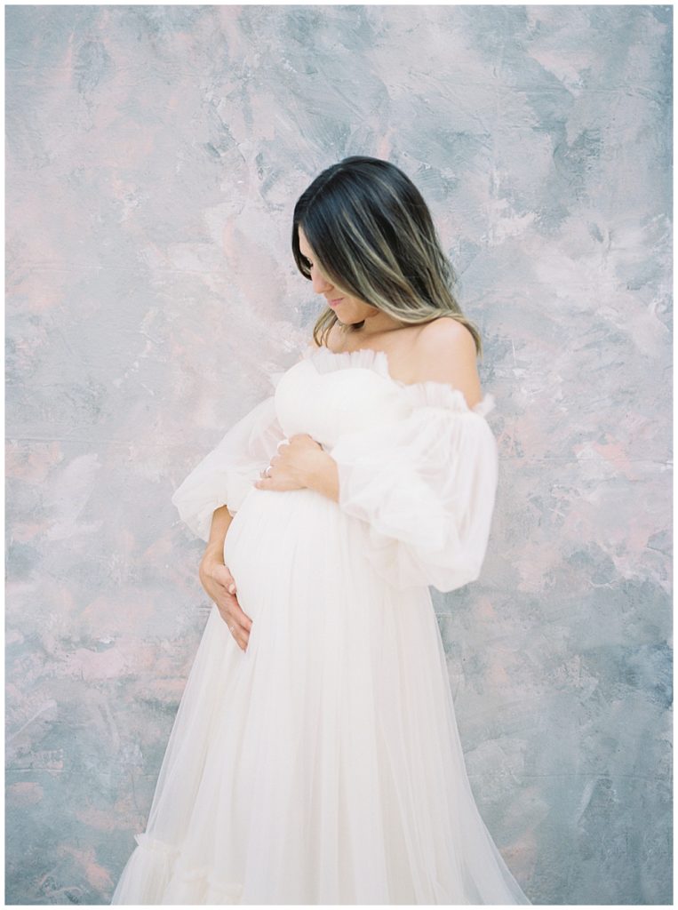 Pregnant Mother Stands With Her Hands On Her Belly During Her Maternity Session In A Dc Photography Studio