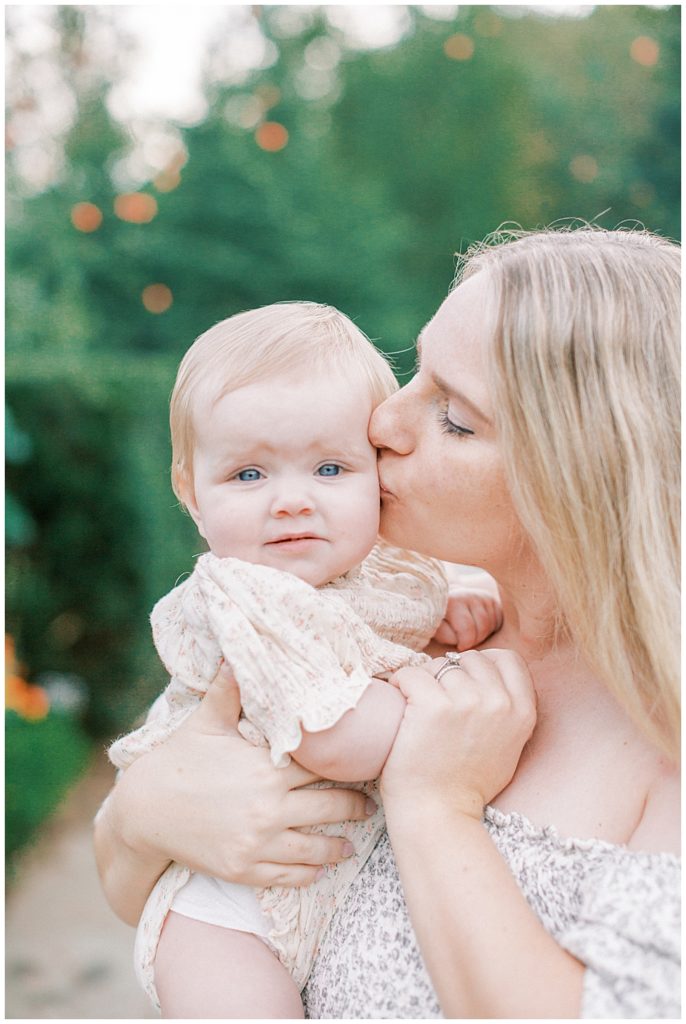 Mother Kissing Her Baby Girl In A Garden