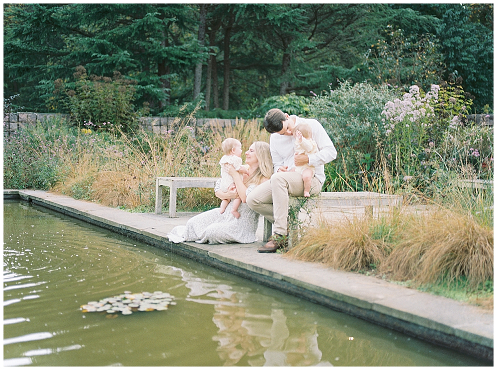 Family Sits By A Pond In A Garden