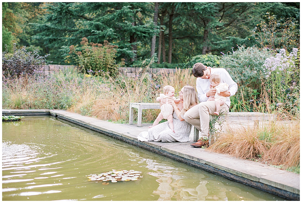 Mother, Father, And Twin Baby Girls Sit By A Pond