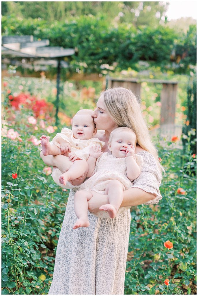 Mother Holding And Kissing One Of Her Twin Baby Girls On The Head