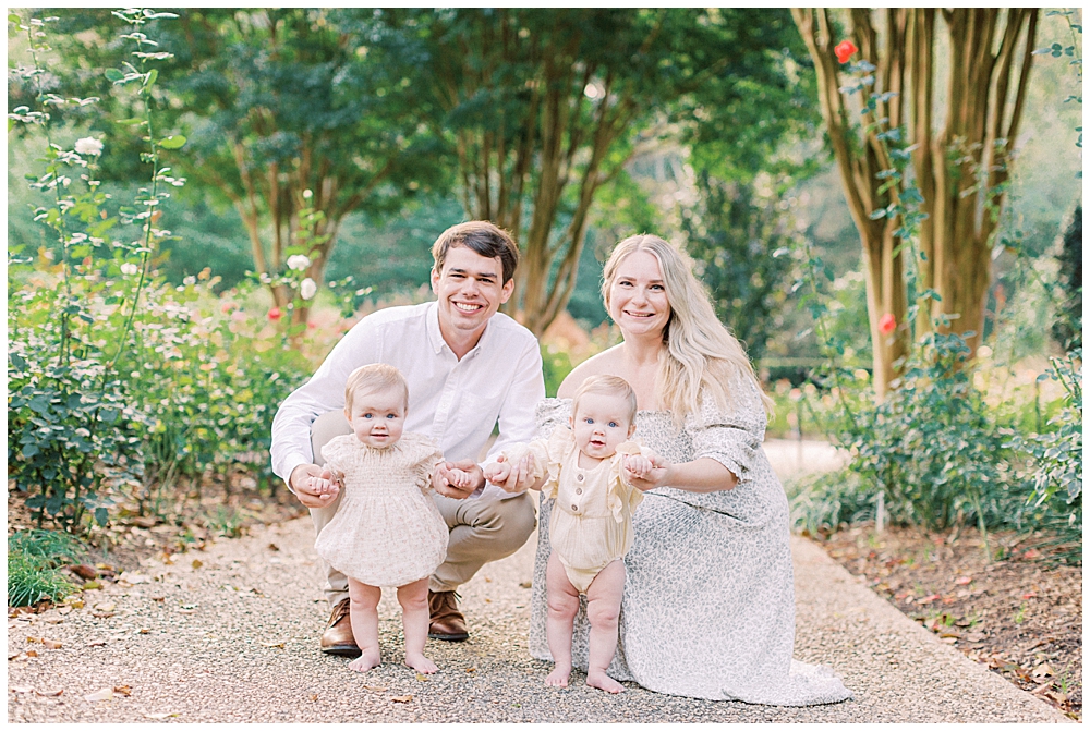 Mother And Father Holding The Hands Of Their Baby Twin Girls While They Stand Up