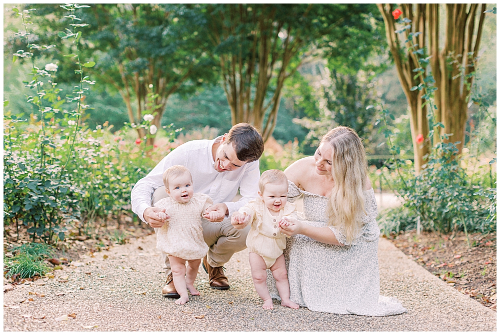 Mother And Father Holding Up Their Twin Babies While They Try To Stand