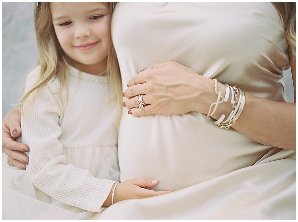 Little Girl Hugs Her Expecting Mother During Their Studio Session