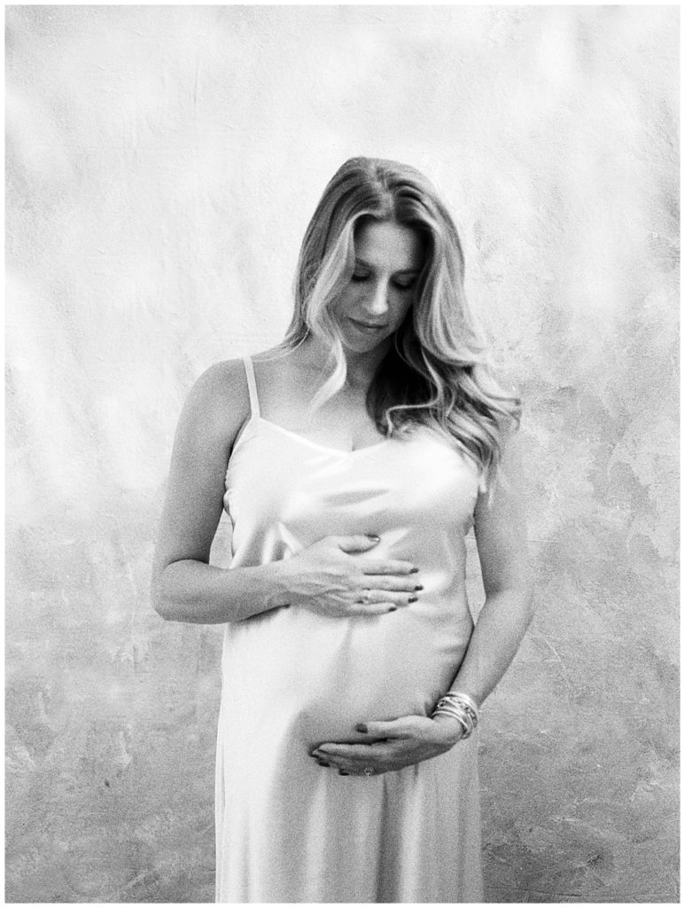 Black And White Image Of Mother Looking Down At Her Pregnant Belly